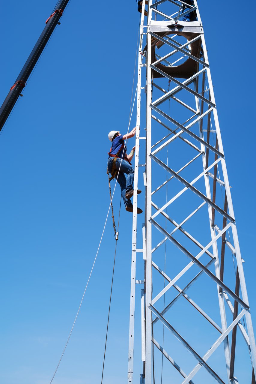 A fitter climbs the stairs of a wind turbine truss tower